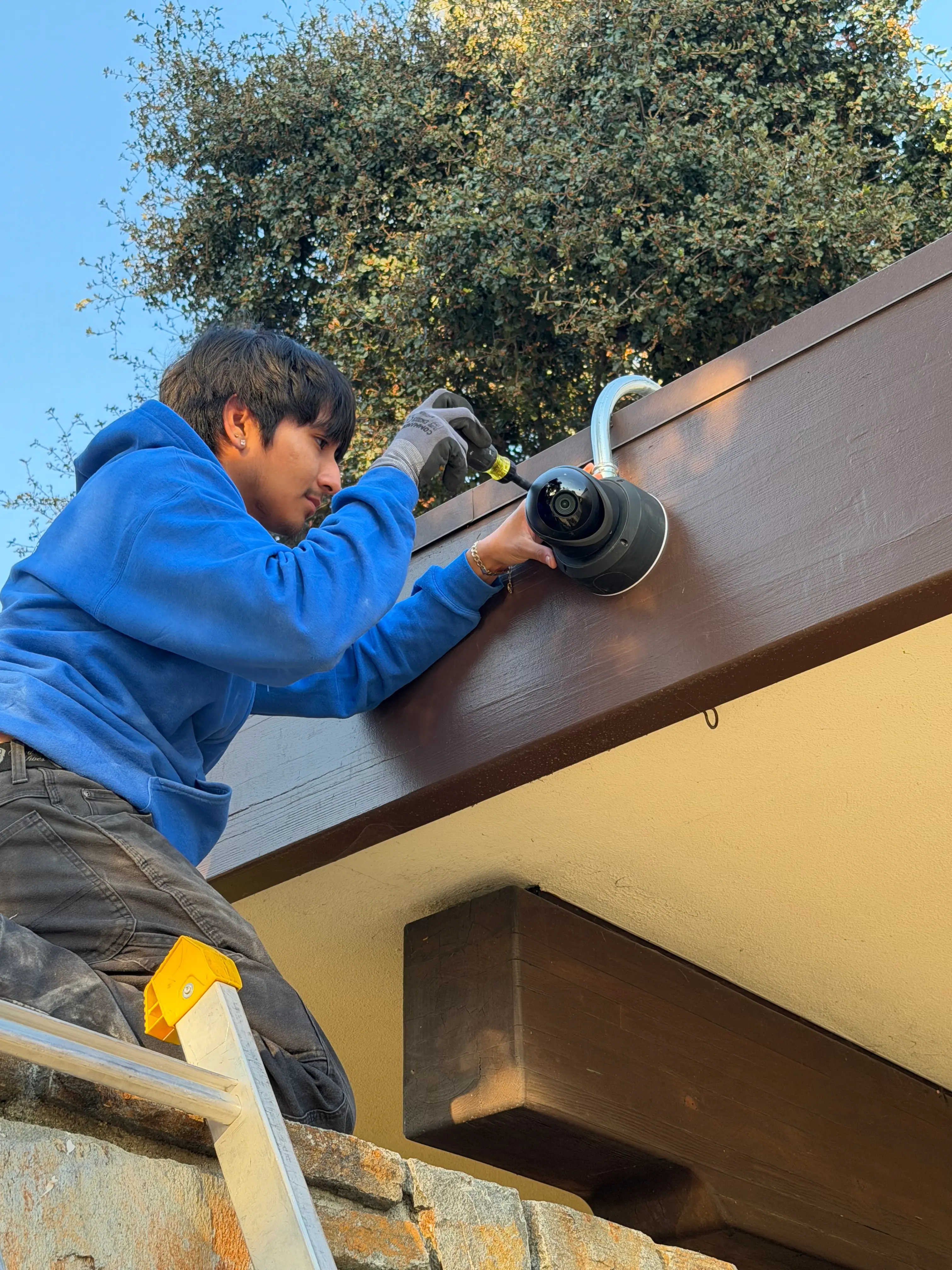 Technician mounting a security camera to a fascia board with conduit already run