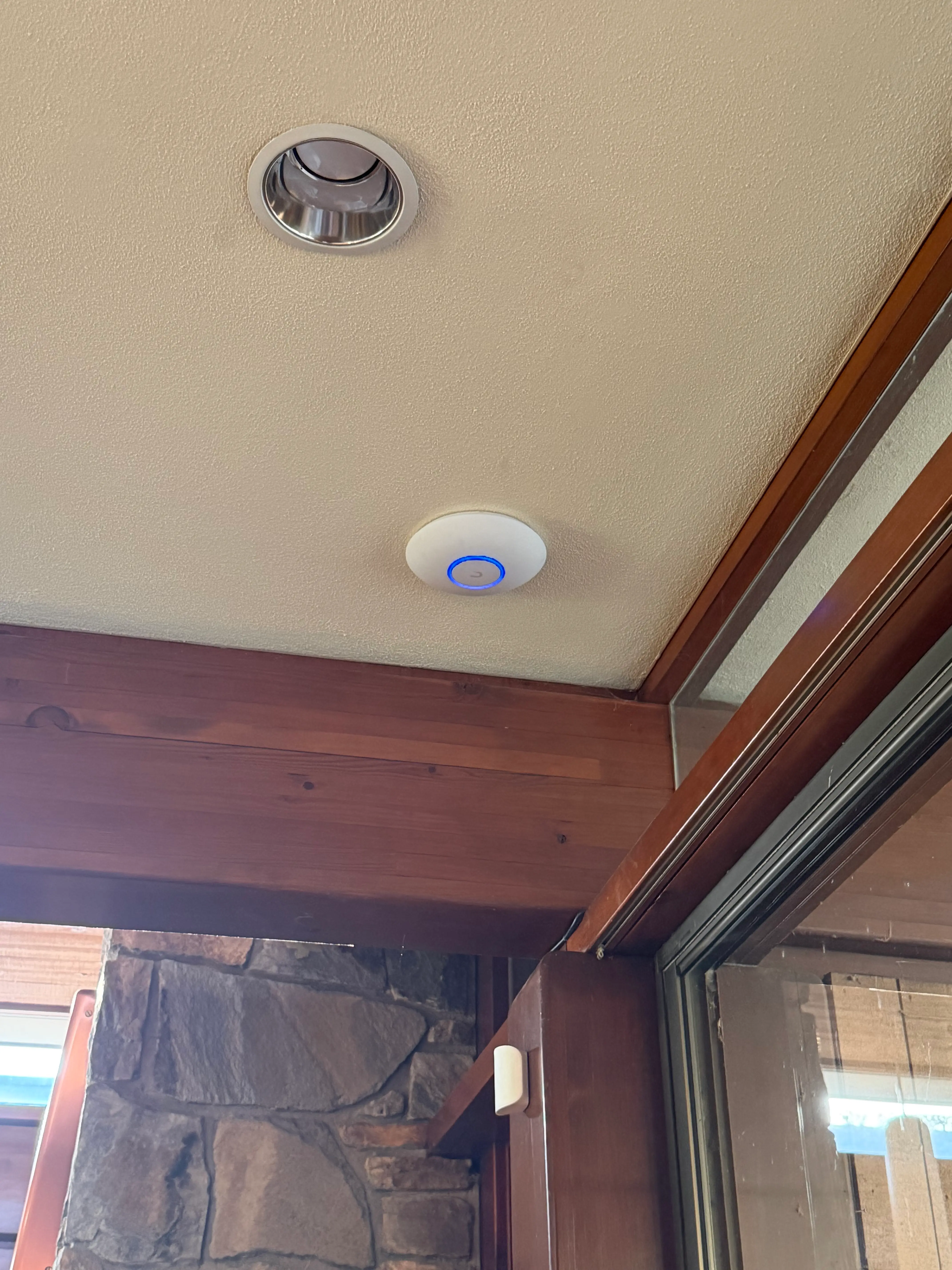 Ubiquiti U7 Pro access point mounted flush on a ceiling near a recessed light fixture in a hillside home