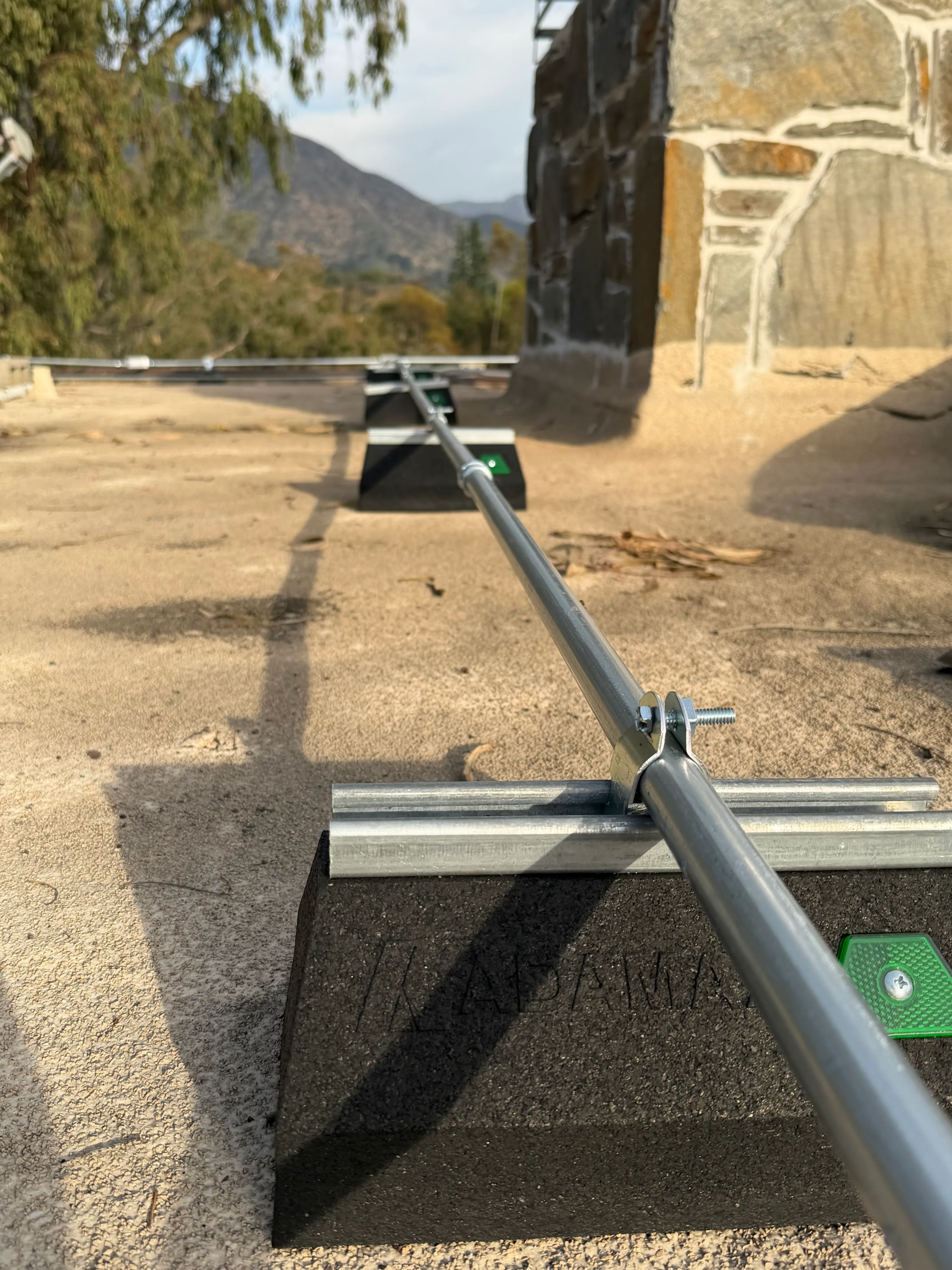Rigid conduit run with pipe supports across a flat roof, engineered to protect network and camera cabling on a hillside estate