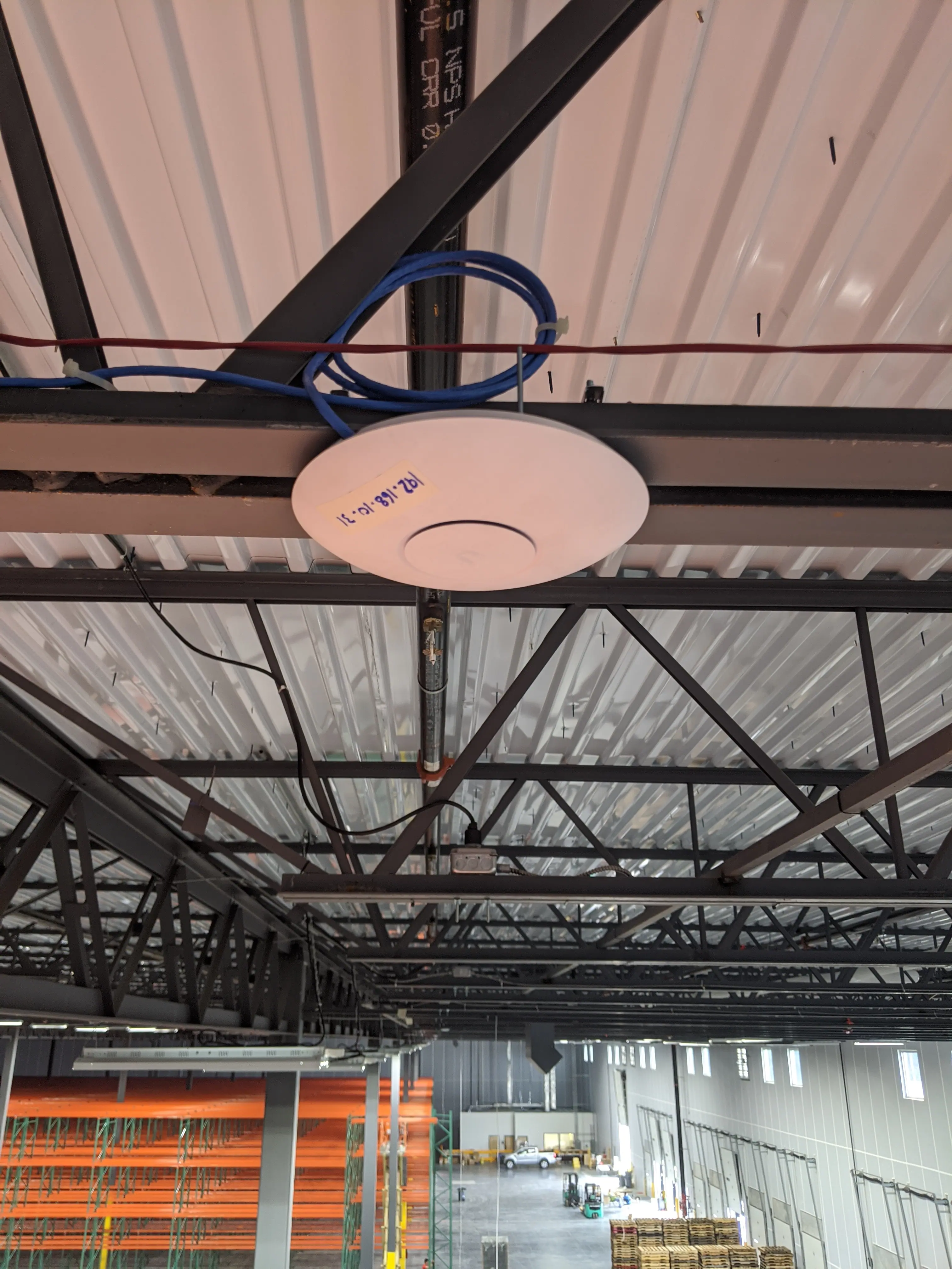 Ubiquiti U6 Pro access point mounted to warehouse roof structure, wired with CAT6